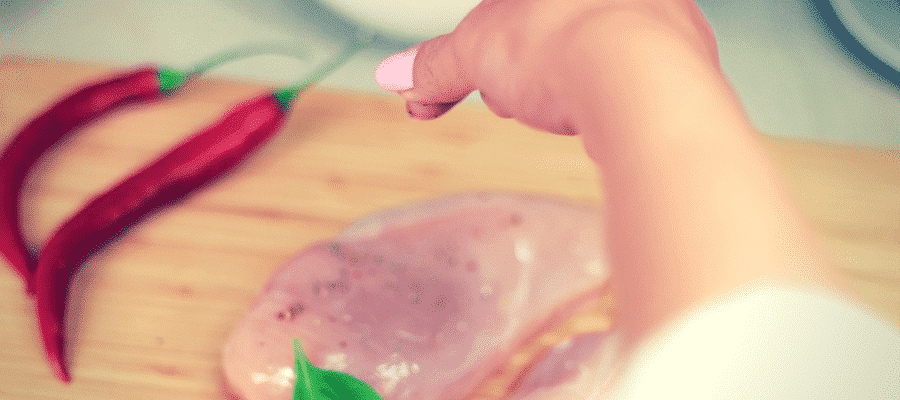 Woman seasoning chicken breast