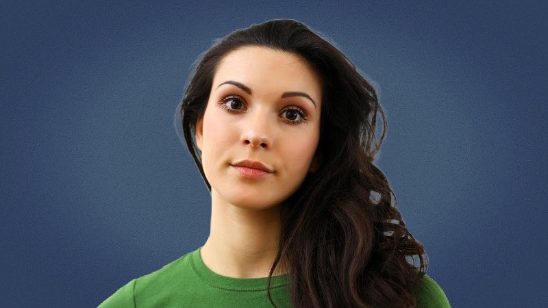 Attractive brunette woman smiling at camera on blue background in green shirt 1