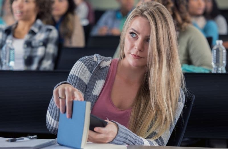 Blonde hiding smartphone with book