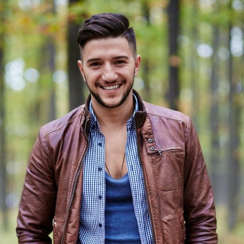 Cheerful man with a triangle shape face and a pompadour with a medium fade and shaved part