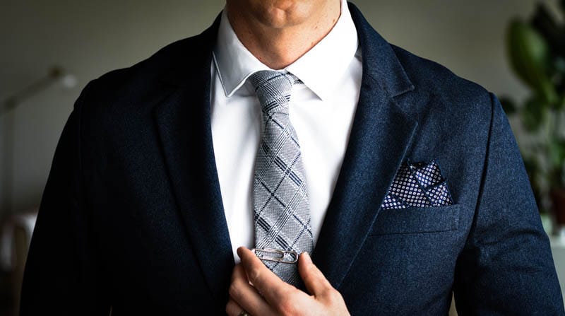 closeup of gentlemens collective tie on model paired with navy suit and white shirt