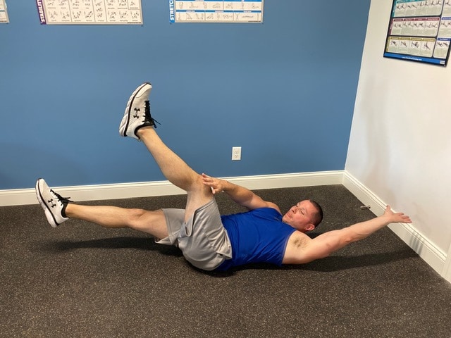 Fitness model performing dead bug indoors with stretch