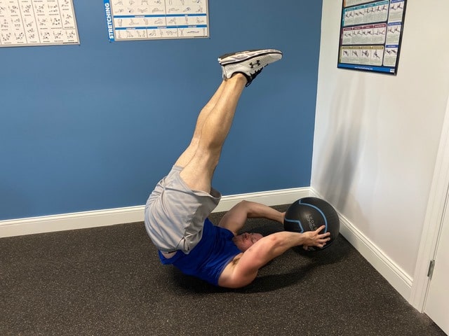 Fitness model performing reverse crunch leg raises indoors