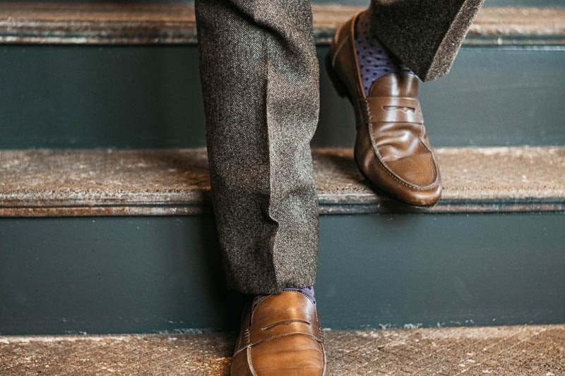 Gentlemans Box Classic walking down steps in brown suit purple socks