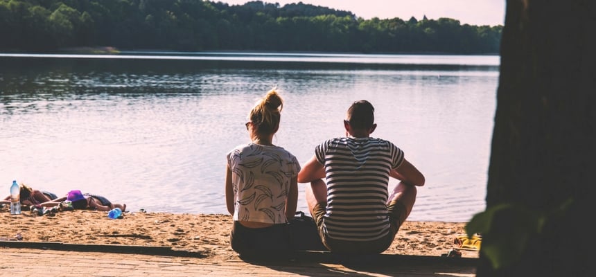 Girl and guy on a date looking at the water sitting down