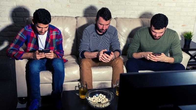 Group of male friends all on their phone while hanging out