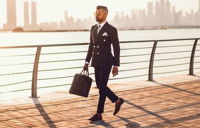 How to wear a gray suit with brown shoes Image of model outside carrying briefcase and wearing double breasted gray suit with brown shoes and no socks