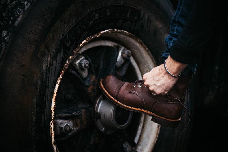 lacing up red wing iron ranger against rusty tire