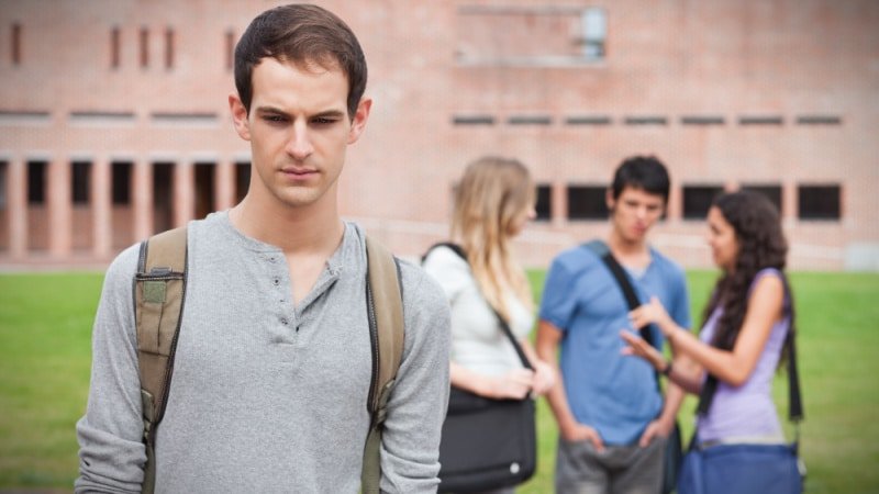 Lonely Student Gamma Male with Friendship Circle Behind Him in Background