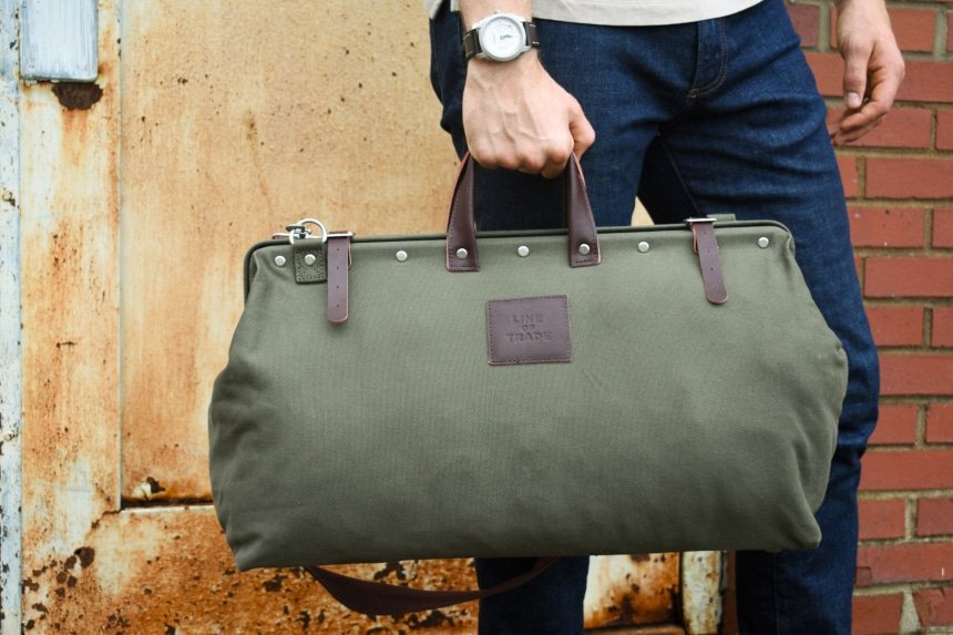 Male Model Holding Bespoke Post Weekender Bag Outside While Wearing Watch and Jeans