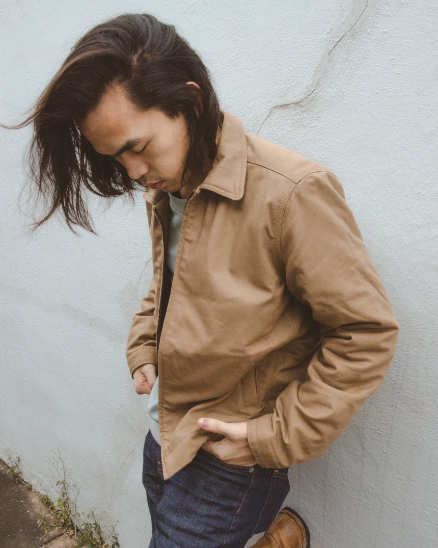 Male model leaning against a wall wearing Everlane Midweight Canvas Jacket, Fleece Crew, and Skinny Fit Jean