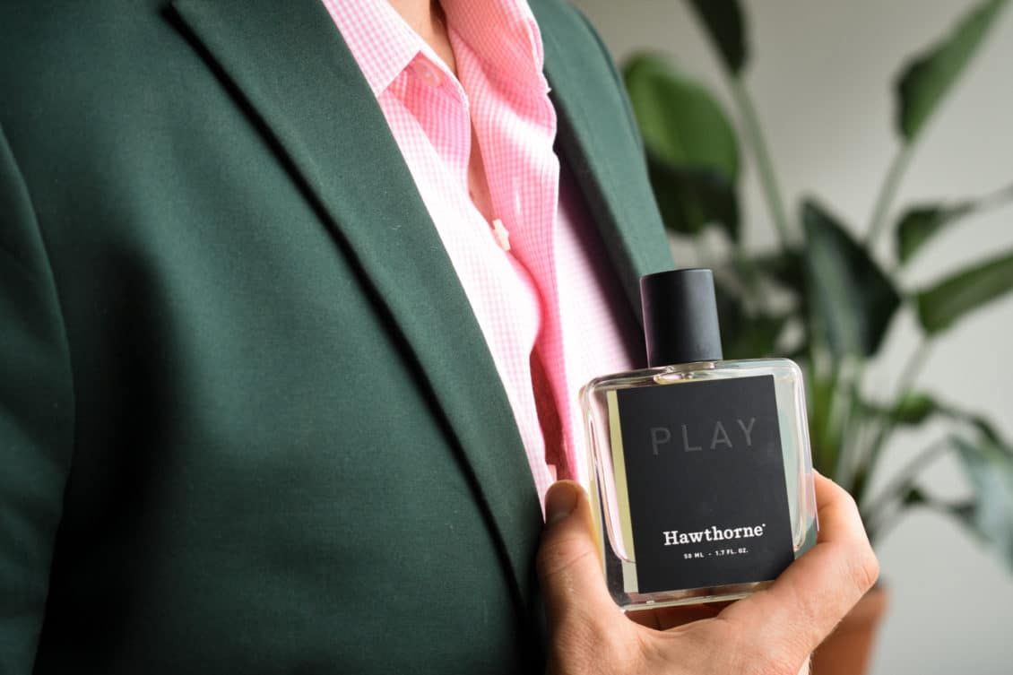 Male Model Wearing Charcoal Suit With Pink Shirt And Holding Hawthorne Play Fragrance Side Angle