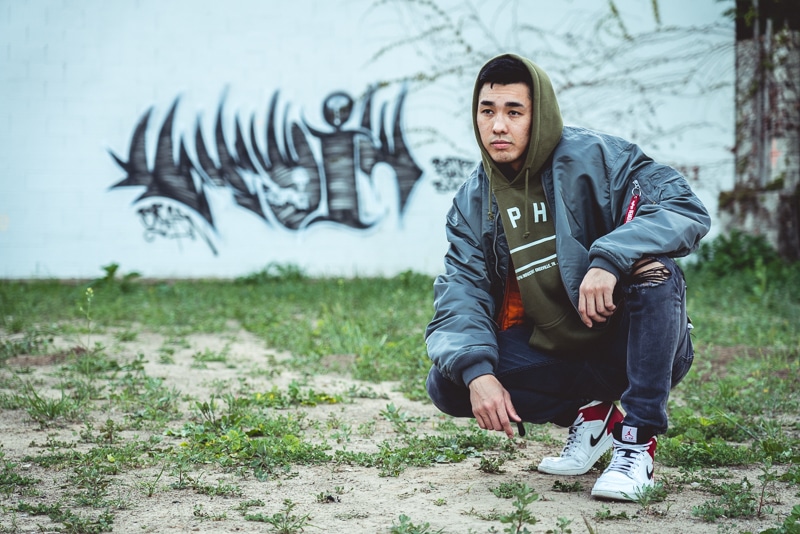 How Military Style Can Level Up Your Closet: The Complete Guide for Men 3 Man crouching in front of graffiti in bomber