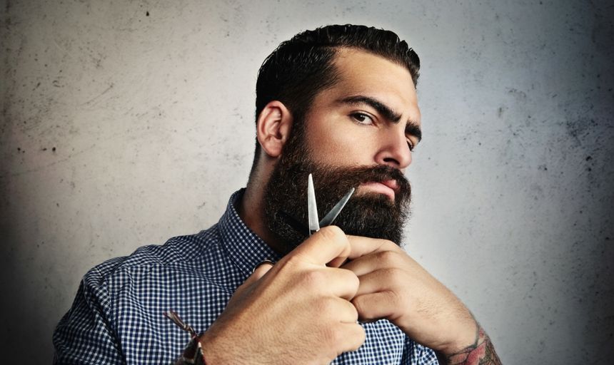 Man cutting beard with scissors with a mean face