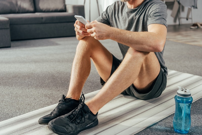 Man doing home workout using phone between sets