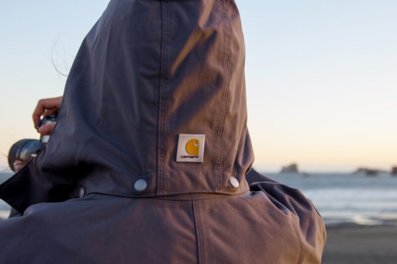 Man holding camera and taking photos while wearing Carhartt Shoreline Jacket at the ocean