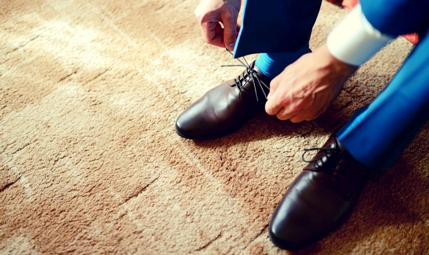 Man in blue suit with brown shoes tieing shoelaces