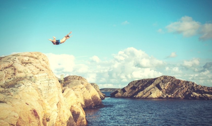 Man jumping off of rock into the water