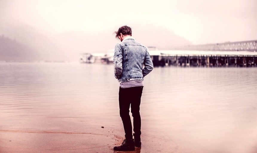 Man near water with denim jacket looking away