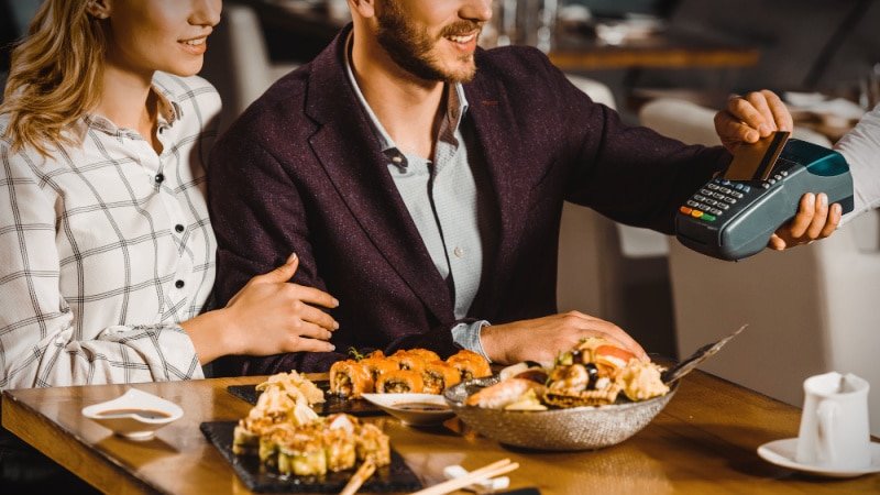 Man paying bill after eating at restaurant with woman