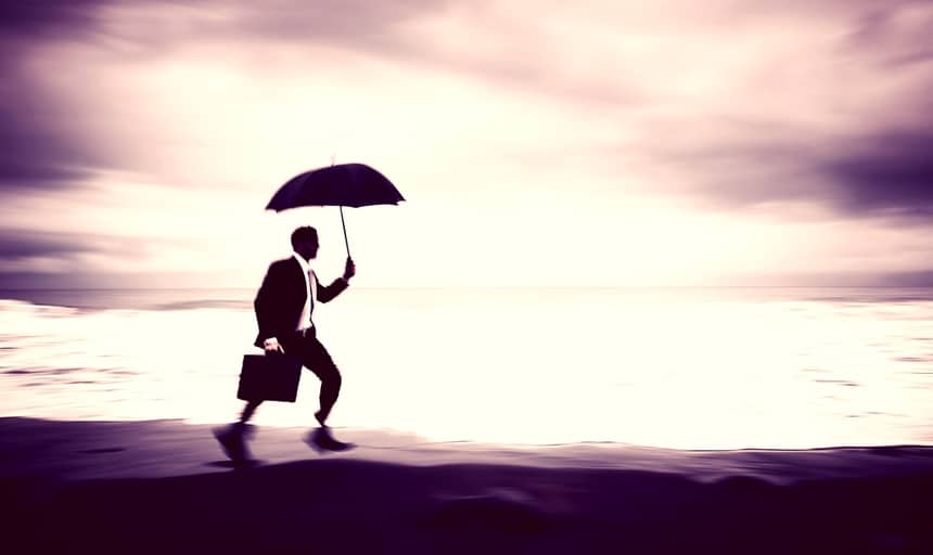 Man running along the beach with umbrella and briefcase