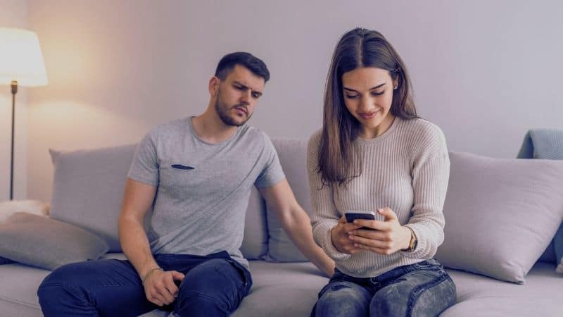 Man spying on girlfriend on phone on couch