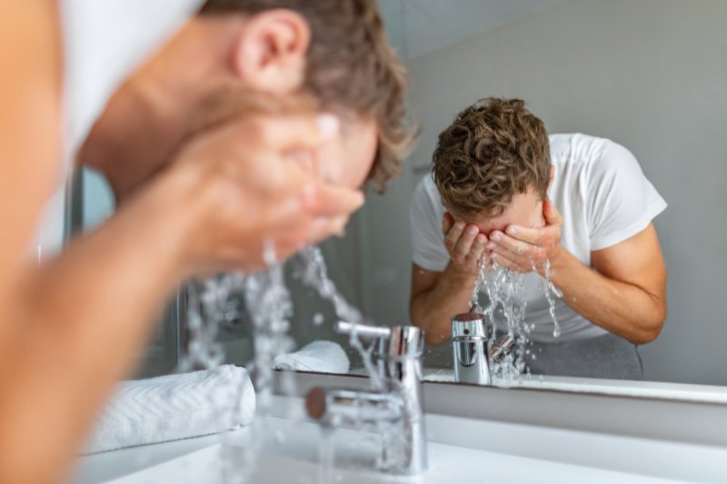 man washing face with warm water