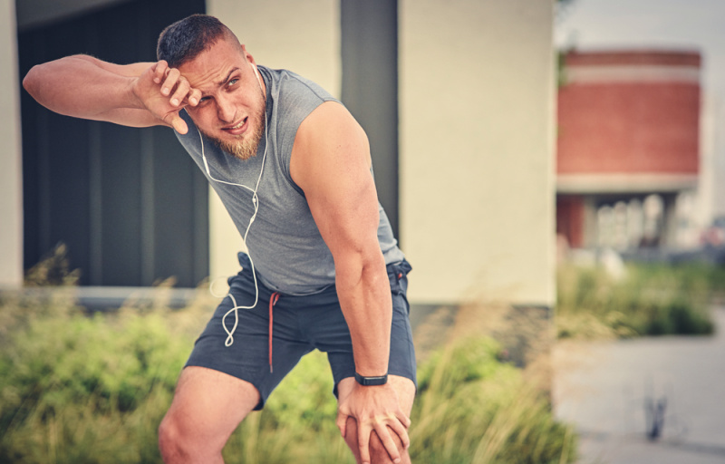 Man wearing headphones and tired from running