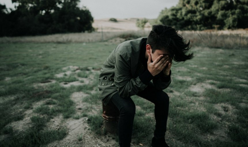 Man with his head in his hands in an open field