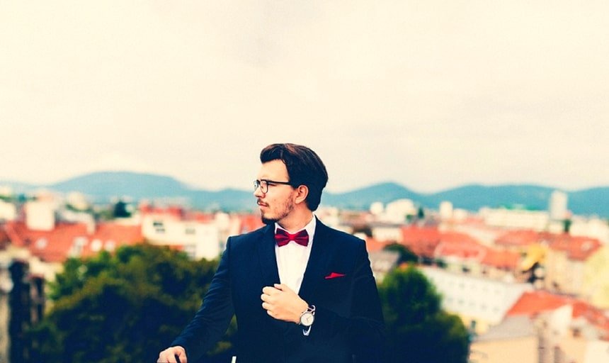 Man with red bow tie and suit outside with great view