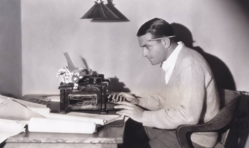 Man writing on a typewriter with pencil behind his ears - vintage in black and white