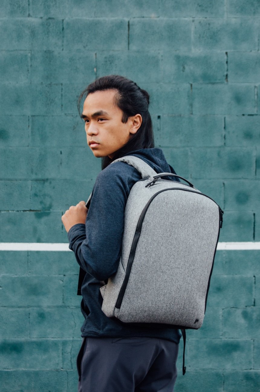 Model Carrying Public Rec Pro Pack On Shoulder And Looking Into Distance Against Aqua Wall