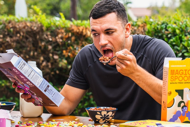 Model eating Magic Spoon and reading cereal