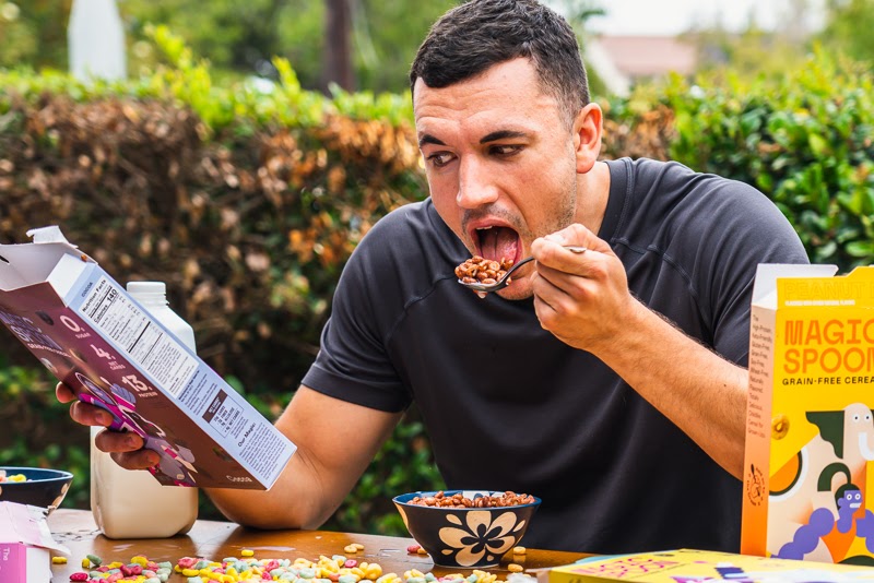 Model eating Magic Spoon and reading cereal