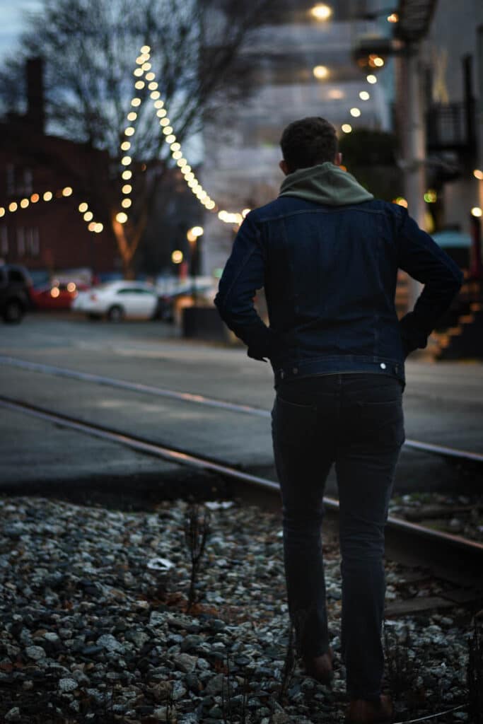 model facing away from camera walking train tracks dawn