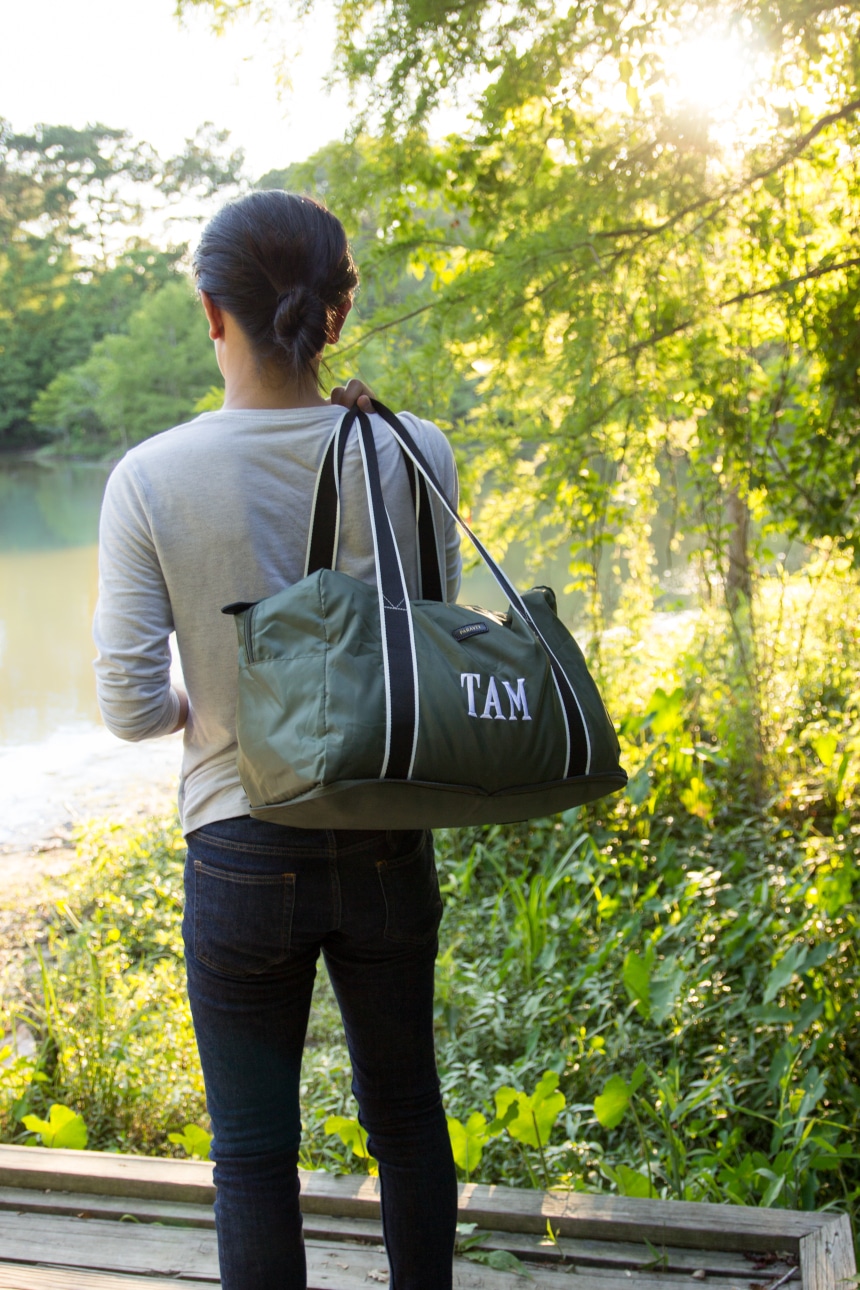 Model Holding Paravel Fold-Up Bagin Safari Green Over Shoulder Outside Near the Water Vertical