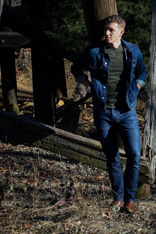 model in canadian tuxedo navy jeans with green sweater and denim jacket