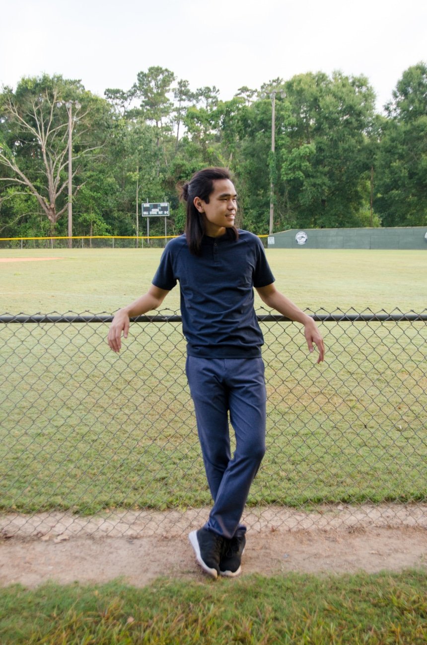 Model Leaning on Fence Wearing Public Rec Products Including All Day Every Day Pant