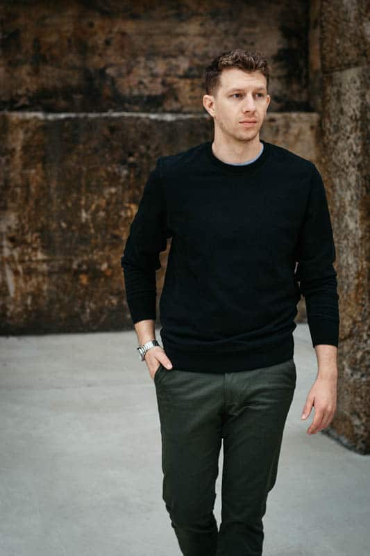 model looking left with olive chinos and black crew neck sweater