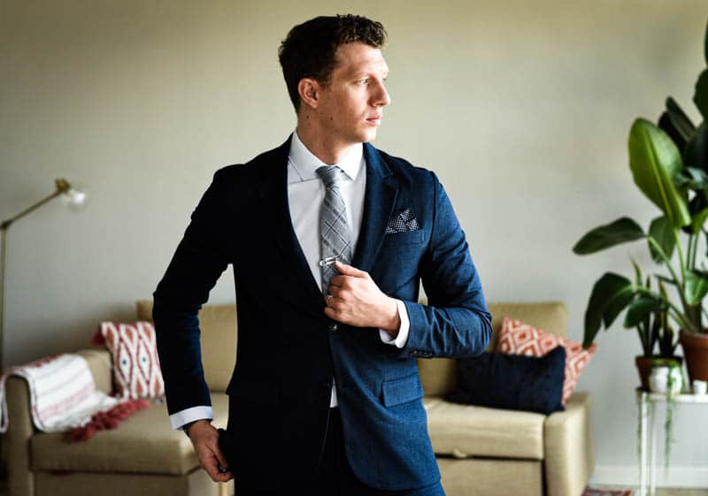 model looking to side wearing navy suit and gentlemens box accessories