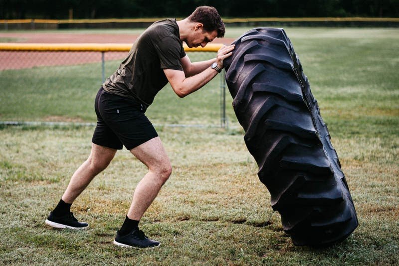 model pushing tire while wearing vuori kore workout shorts