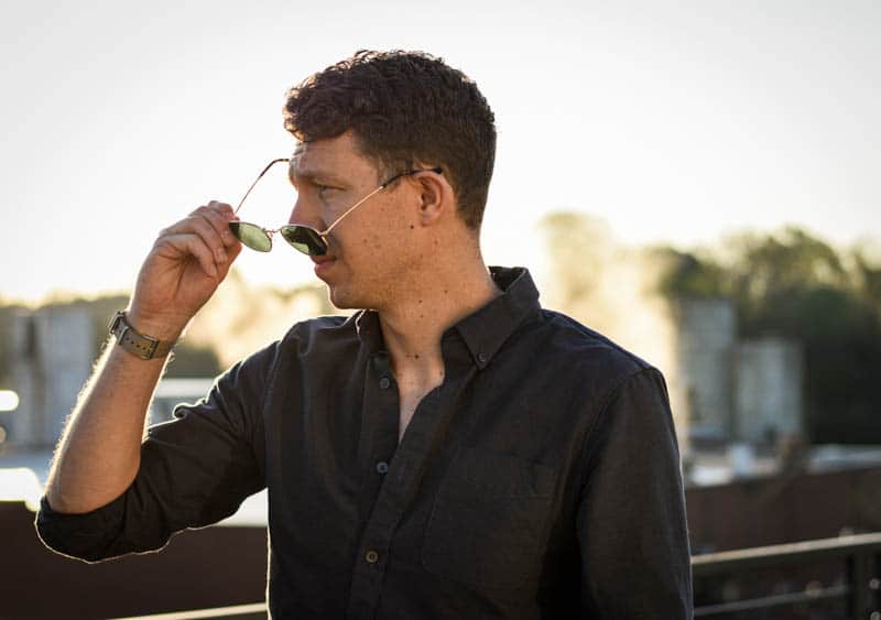 model removing whiskey shiner hexagram sunglasses against foggy background