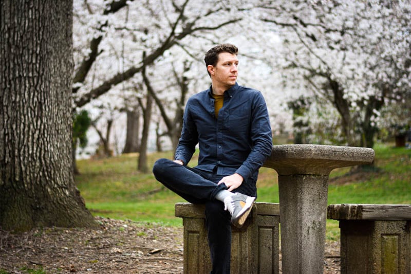 model sitting at bench with everlane tread sneakers blossoming trees in background