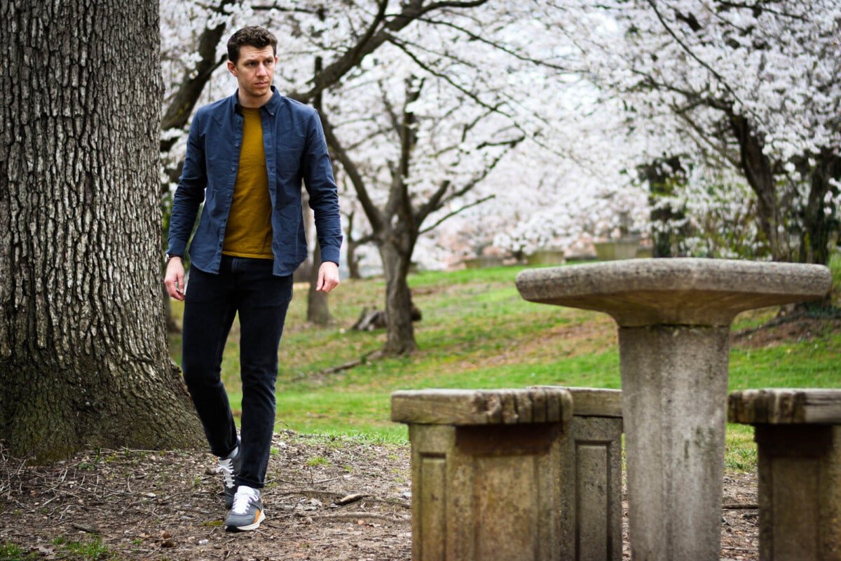 model sitting at bench with everlane tread sneakers blossoming trees