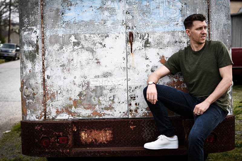 model sitting on beat up van with green t shirt and white sneakers rb1 low from rag and bone