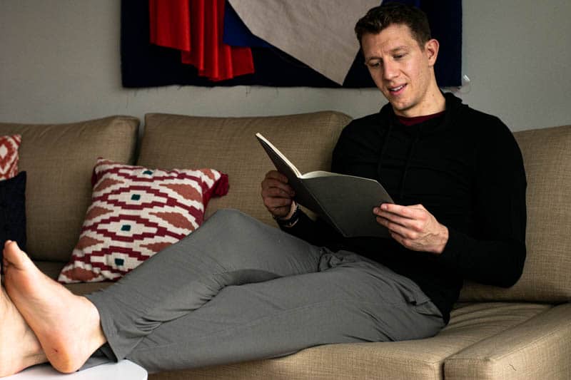 model smiling reading book with meundies black hoodies and grey loungwear