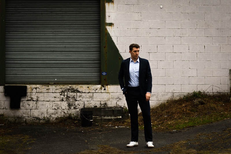 model standing wearing navy suit and white sneakers