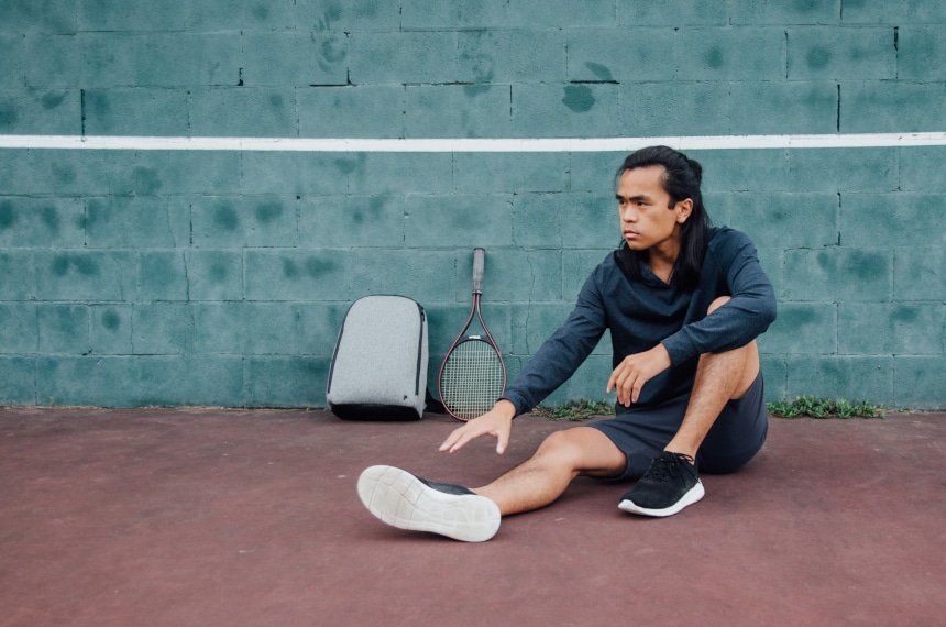 Model Stretching Against The Wall Wearing Public Rec Apparel And Sitting Next to Pro Pack