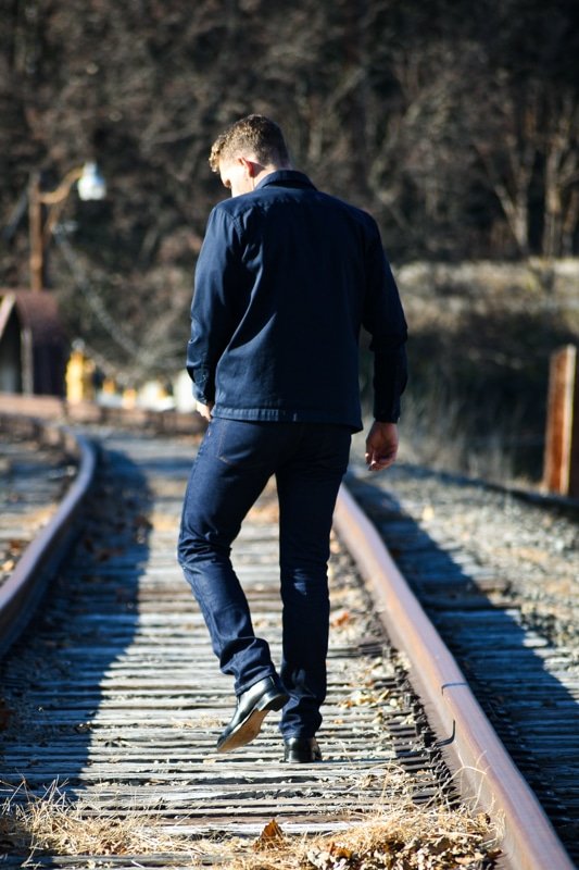 model walking down train tracks dark blue jeans and black boots
