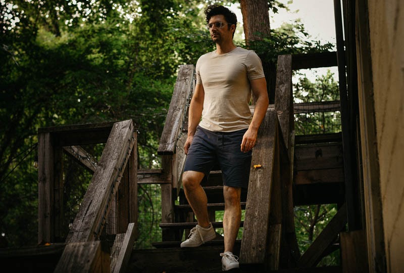 model walking down wooden steps wearing basic man shirt and public rec shorts